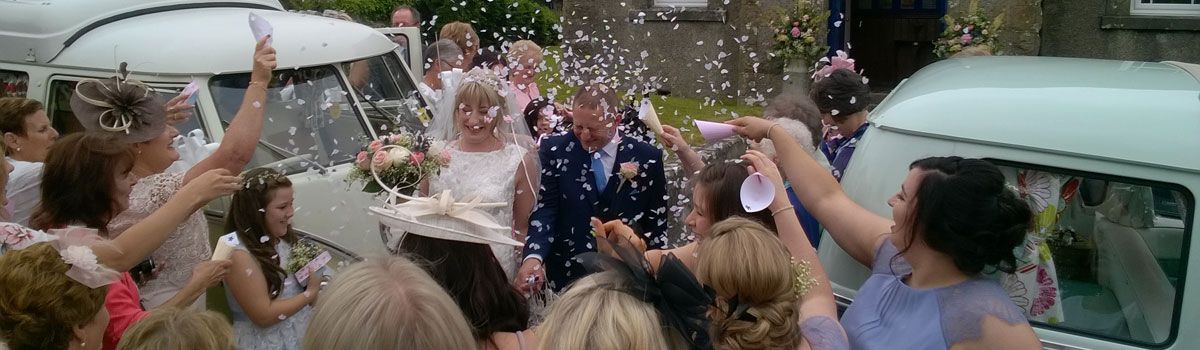 Wedding couple marries in North Wales having confetti thrown next to VW Campervans hired by Hilltop Classics